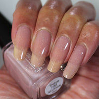 Hand with nude nail polish holding a bottle of nail polish